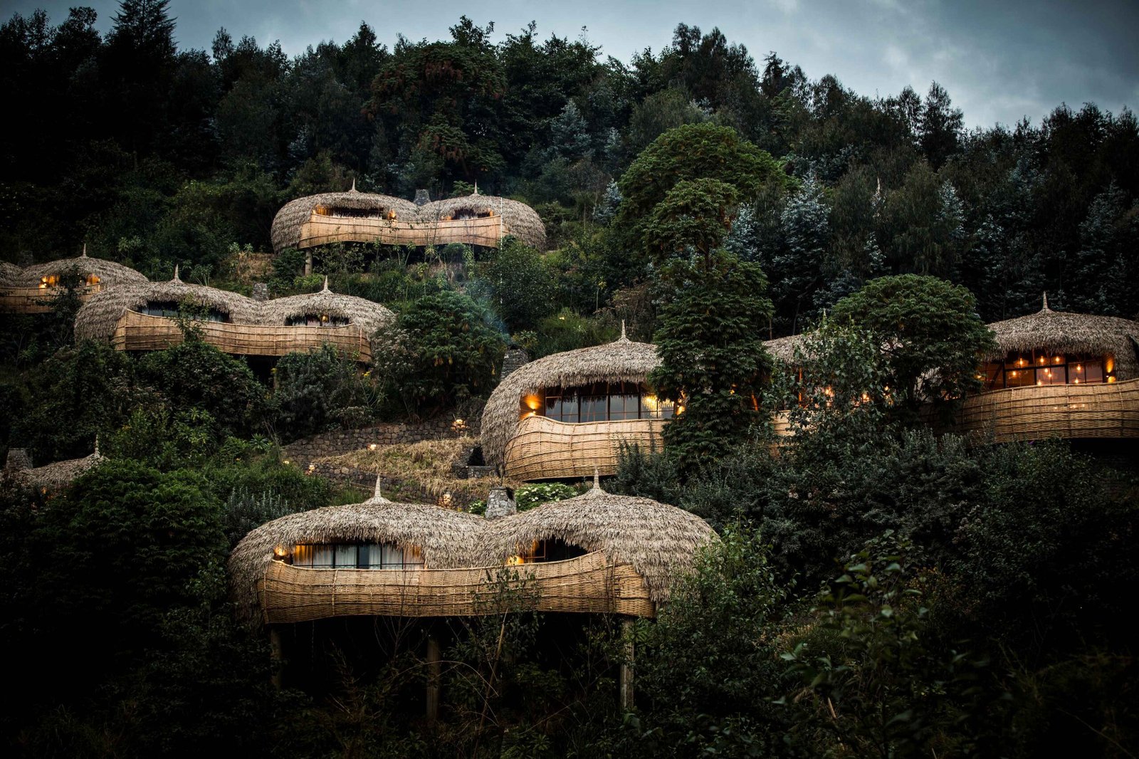 Round woven villas of a private lodge among forest trees near Volcanoes National Park, Rwanda
