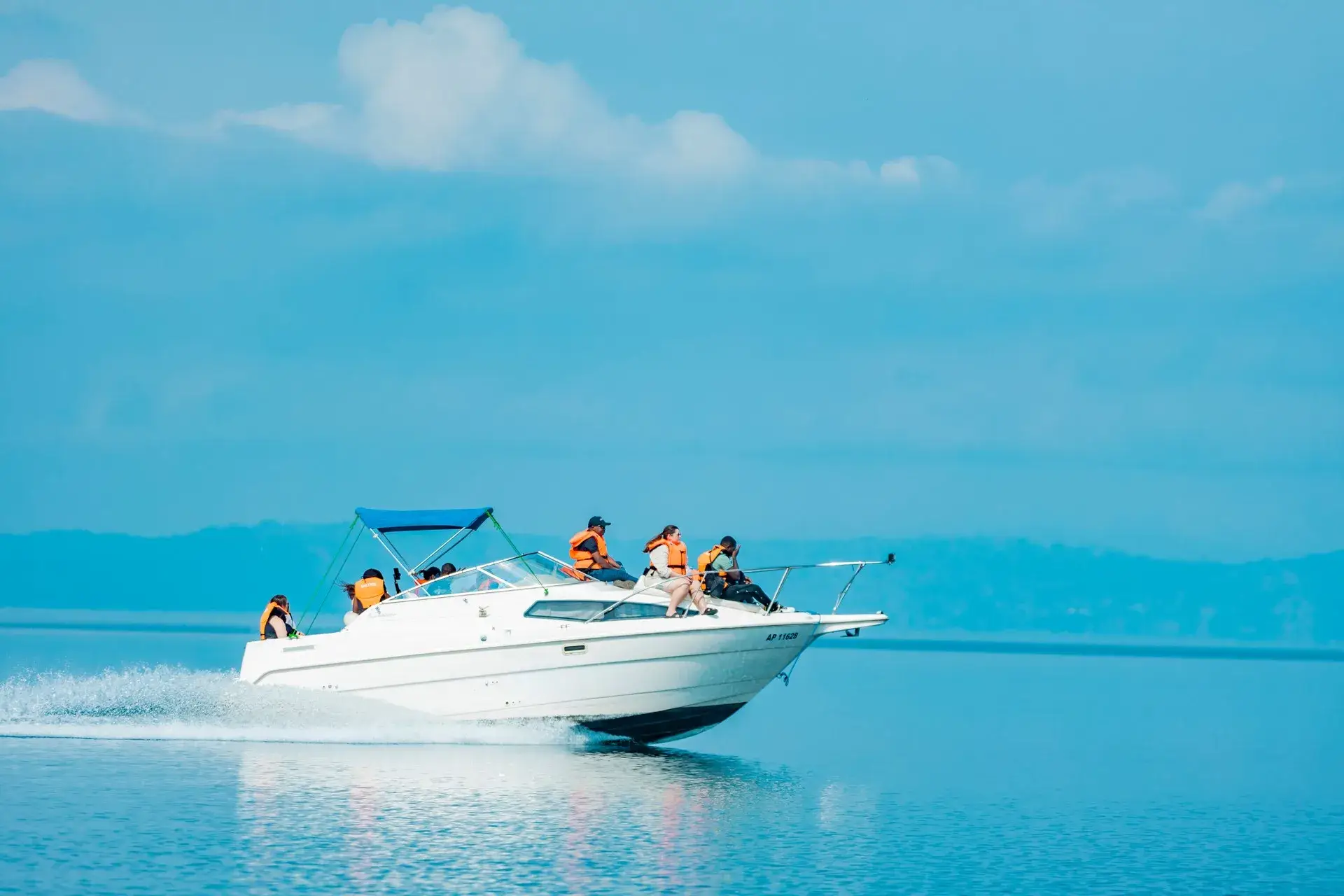 A speedboat with passengers in life jackets crossing the calm blue water of Lake Kivu, Rwanda