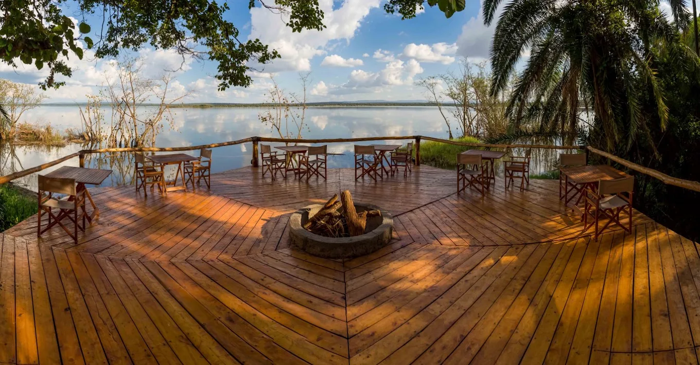 A timber deck with chairs and a fire pit above the lake at Ruzizi Tented Lodge in Akagera National Park, Rwanda