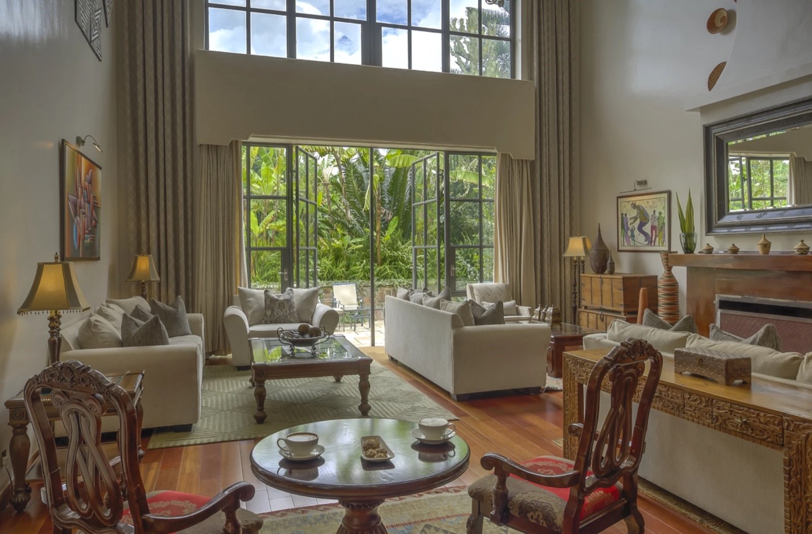 High-ceilinged lounge with sofas and tall windows at The Bishop's House, Musanze