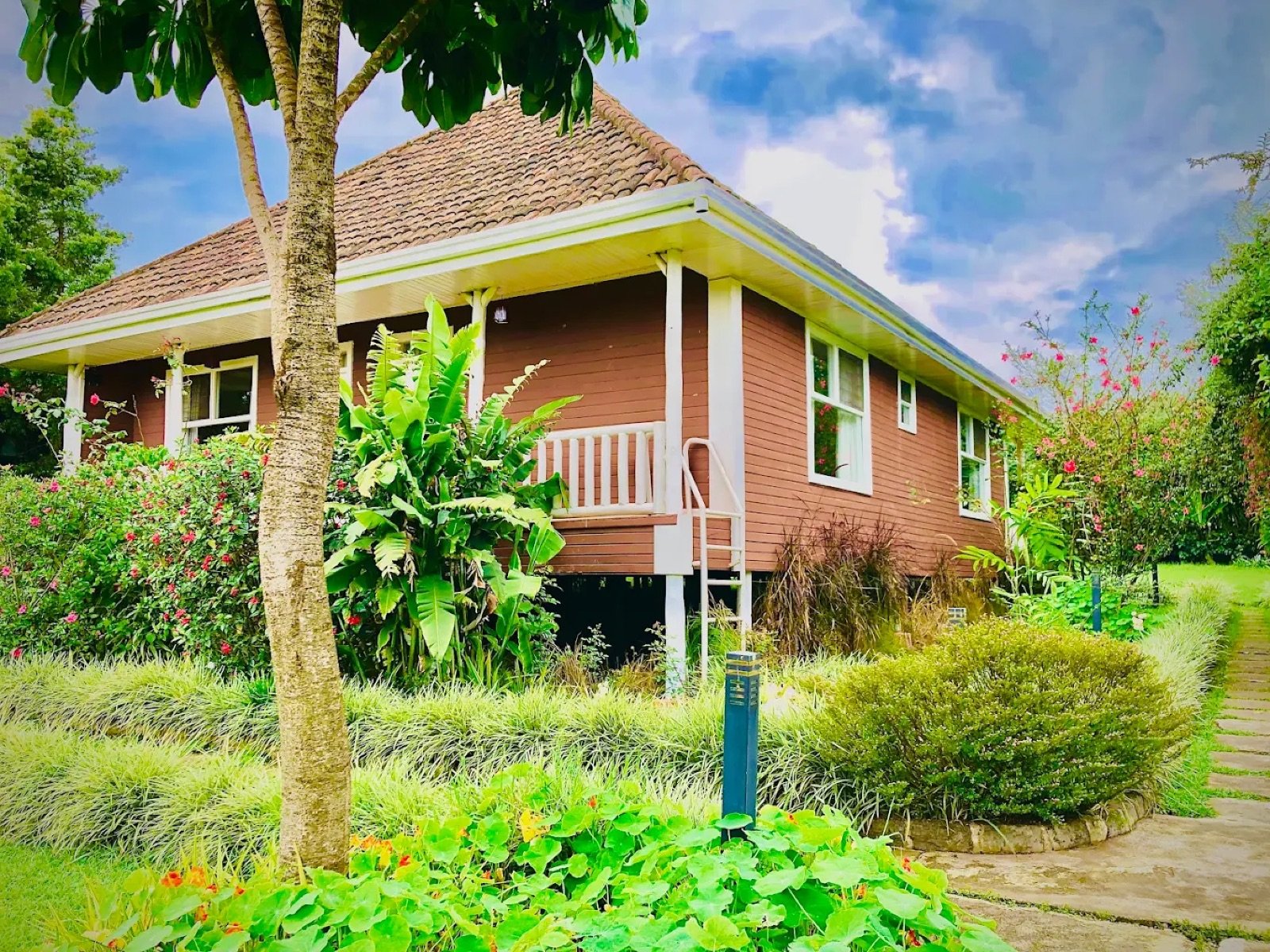 A wooden cottage with a red tiled roof and a garden at Tiloreza